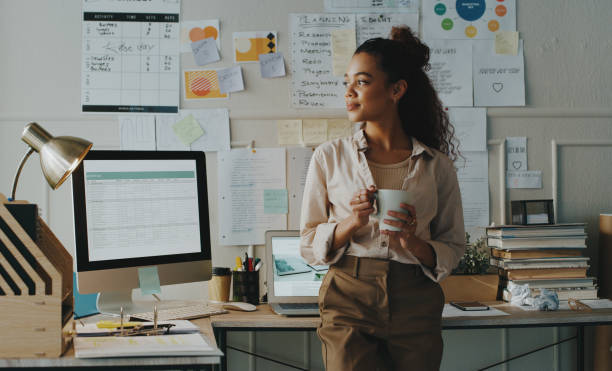 Image of a female digital entrepreneur drinking from a cup with her desktop behind her
